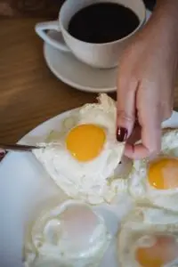 Woman Placing Fried Eggs on the Plate